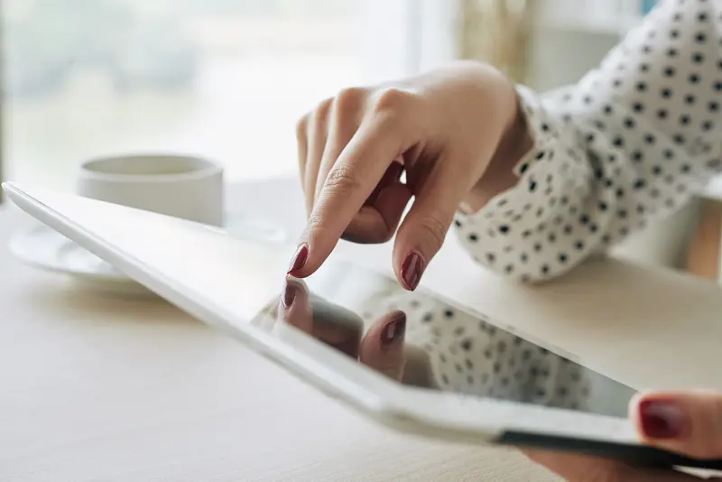 Afbeelding van vrouw met tablet aan de koffietafel