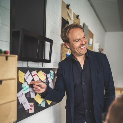 Tijs lachend voor een bord met post-its