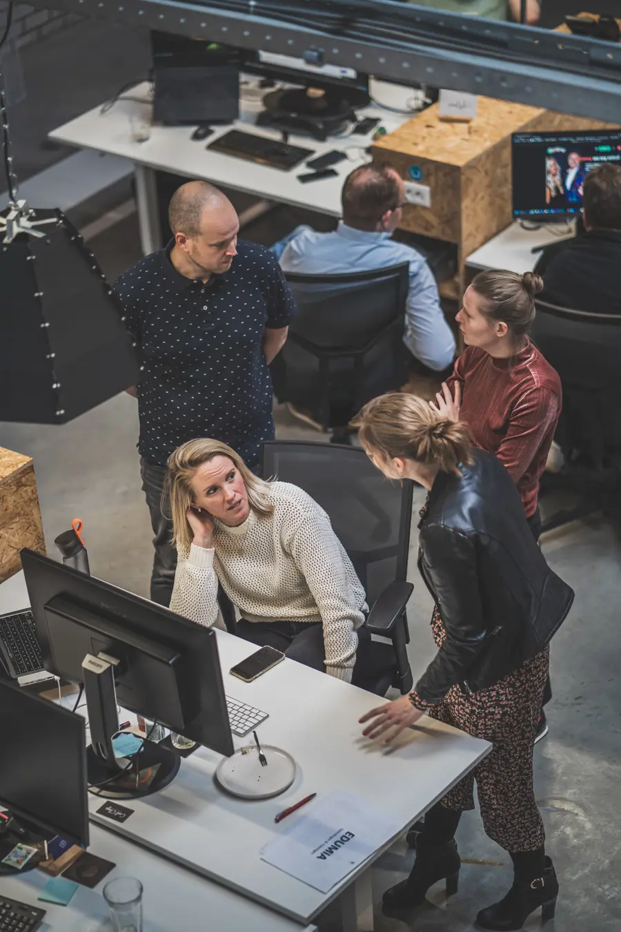foto van bovenaf waar medewerkers vrolijk online aan het overleggen zijn op 2 verschillende plekken