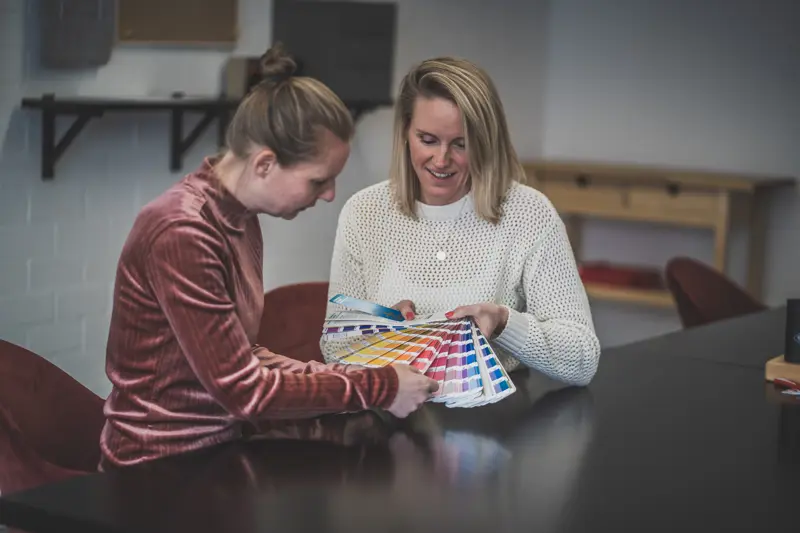 medewerkers Lisa en Mariëlle kijkend naar een kleurenwaaier