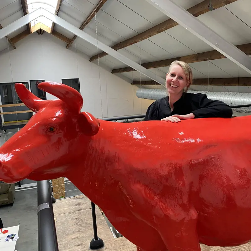 medewerker lisa lachend achter een koe op kantoor