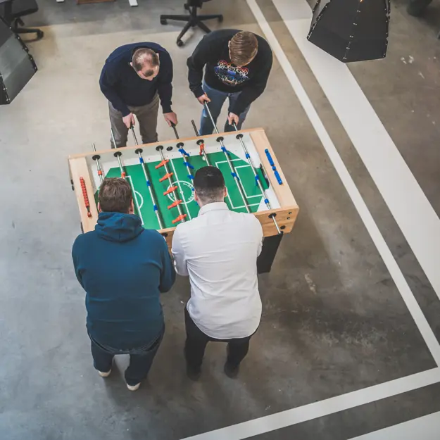 4 medewerkers spelend aan de tafelvoetbaltafel