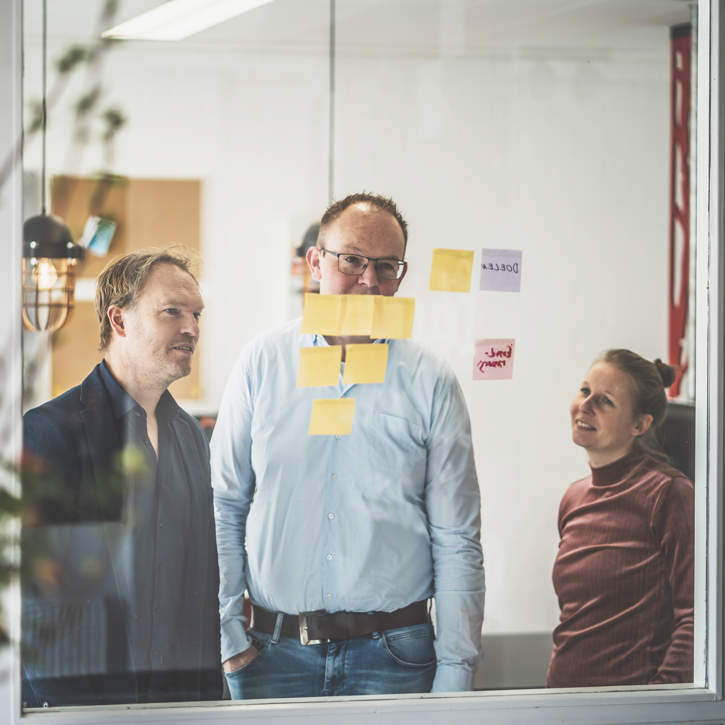 Tijs, Jeroen en Lisa samen achter een raam kijkend naar post-it's